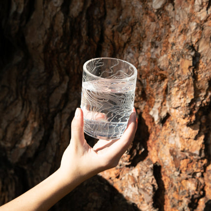 clear rocks glass being held up outside
